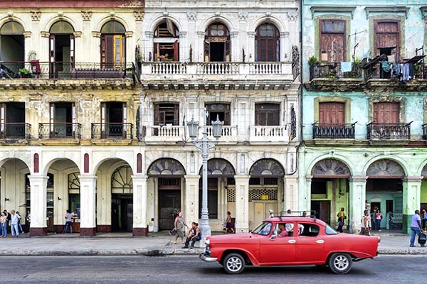 Street scene with vintage car and worn out buildings in Havana, Cuba.