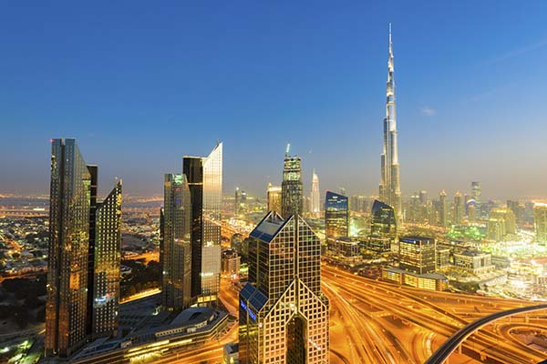 Dubai Downtown at dusk Sheikh Zayed Road and Burj Khalifa are illuminated by bright lights and car light trails. The sky has a blue hour glow and the lights are a warm orange colour. United Arab Emirates. Megacity.